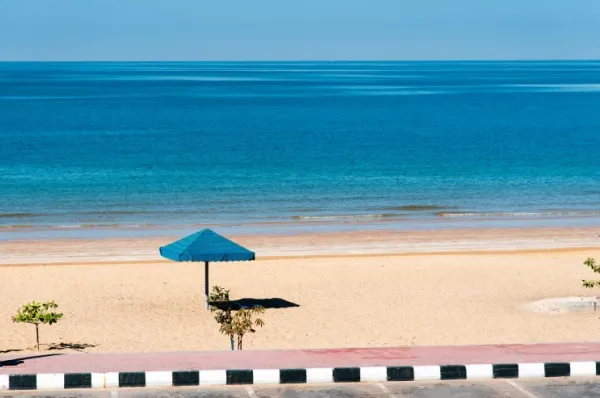 Blauer Sonnenschirm am hellen Sandstrand Flamingo Beach in Ra