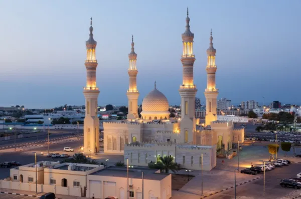 Sheikh-Zayed-Moschee mit vier Minaretten und einer Kuppel in abendlicher Beleuchtung.