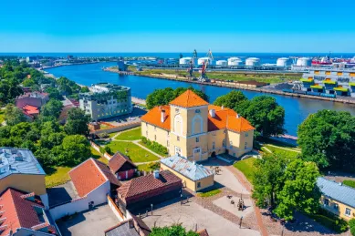 Luftaufnahme der Stadt Windau bei Sonnenschein, gespickt mit alten Gebäuden und dem Fluss Venta.