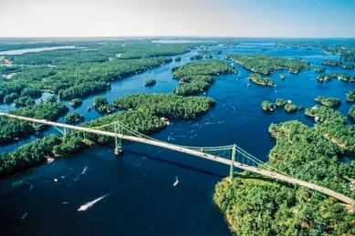 Luftperspektive auf viele kleine, grüne Inseln und eine Brücke auf dem blauen Meer.
