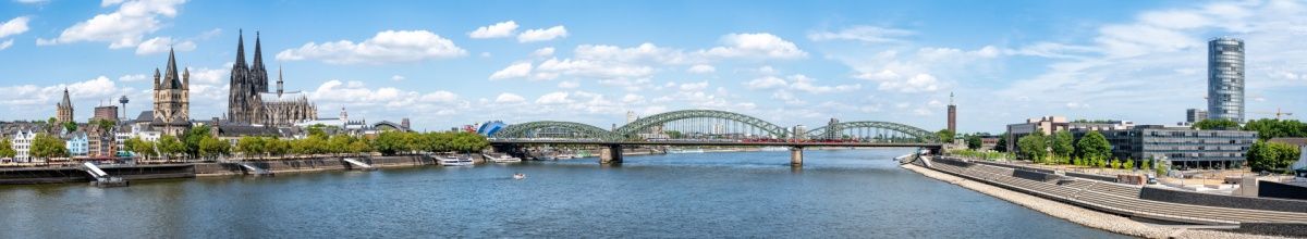 Blick auf Köln vom Rhein aus mit dem Kölner Dom und der Hohenzollern Brücke im Hintergrund.