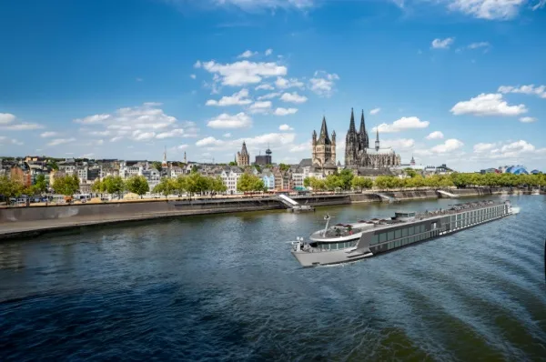 Flusskreuzfahrt ab Köln Flusskreuzfahrtsschiff fährt auf dem Rhein durch Köln, der Kölner Dom im Hintergrund.
