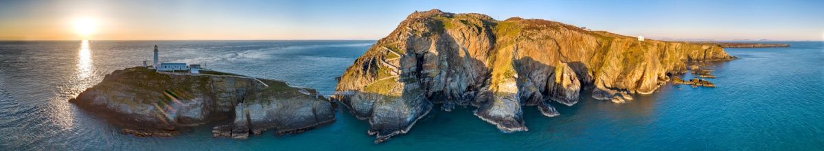 Panoramablick auf den South Stack Leuchtturm, während die Sonne untergeht.