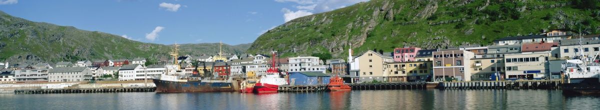 Blick auf die Hafenkante von Kirkenes mit Häuserfronten und Schiffen.