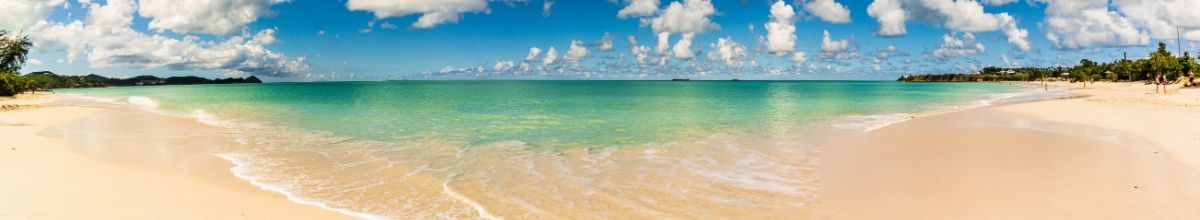 Heller Sandstrand vor türkis-blauem Meer auf Antigua.