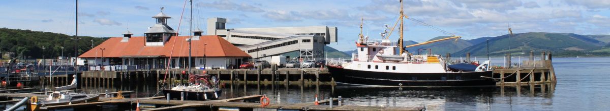 Der Hafen von Rothesay mit einigen Booten, den Piers und dem Hafenbüro bei Tag.