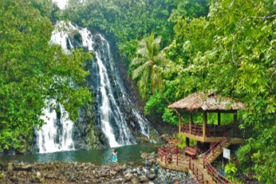 Der Kepirohi Wasserfall auf Pohnpei dicht umgeben von Dschungel und mit einer kleinen Plattform davor bei Tag.