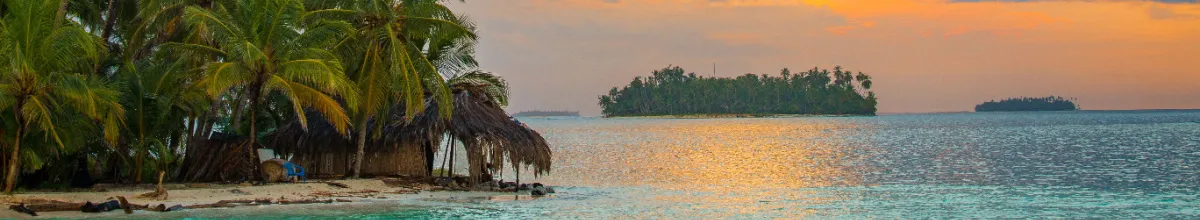 Ein orangener Sonnenuntergang auf den San-Blas-Inseln mit dem ruhigen, glatten Meer im Vordergrund.