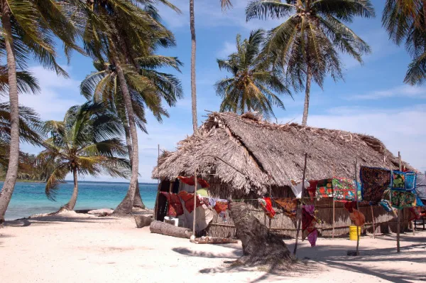 Eine rustikale Strandhütte umgeben von Palmen und feinem Sand an der Küste einer der Inseln.