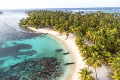 Ein weißer Sandstrand auf den San-Blas-Inseln an einen tropischen Wald angrenzend bei Sonnenschein.