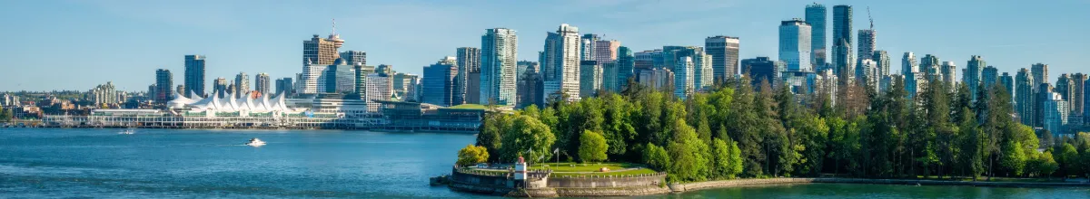 Panorama von Vancouvers Hafenkante bei Tag mit einem Park und der Metropole im Hintergrund.