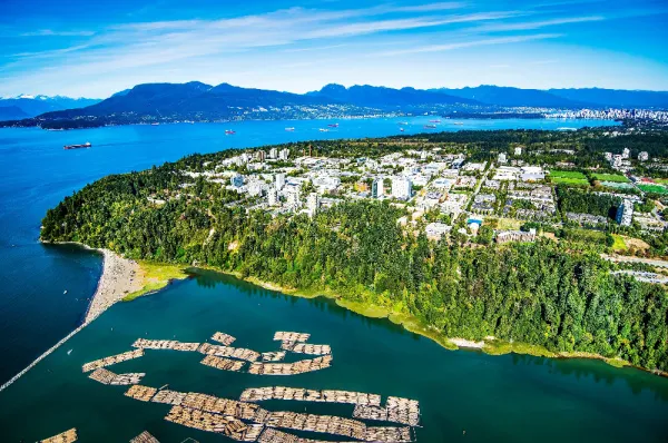 Vogelperspektive der Universität von British Columbia bei Vancouver, umgeben von Parks, Wasser und Bergen in der Ferne.