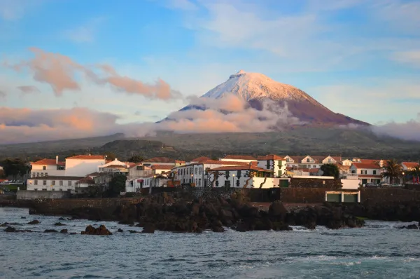 Madalena und der Vulkan Ausschnitt der Stadt Madalena welche vor dem Pico Vulkan liegt, der im Hintergrund in den Himmel ragt bei Sonnenaufgang.