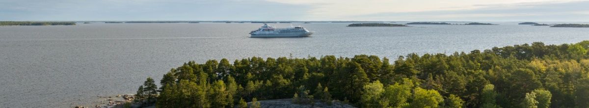 Die Silver Wind fährt auf dem Meer, ein Wald im Vordergrund.