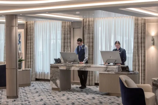 Rezeption, an der zwei Mitarbeitende stehen, an Bord eines Schiffes von Silversea.