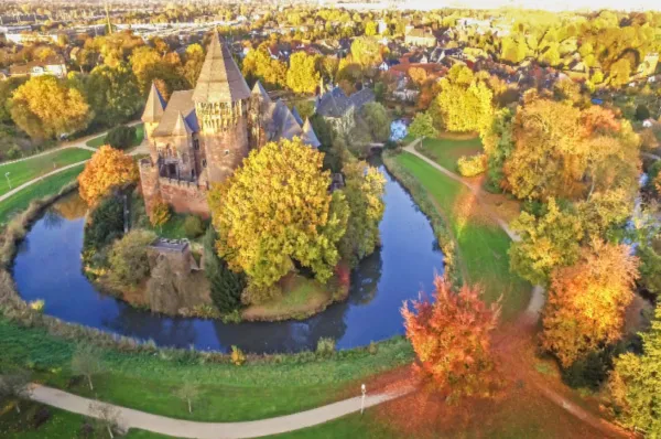 Die Burg Linn Die Burg Linn in Krefeld bei Tag umgeben von einem Park, der in herbstgoldenem Glanz erstrahlt.