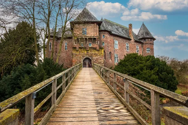 Das Tor der Burg Linn Frontale einer Holzbrücke, die über den Burggraben der Burg Linn geht mit dem mittelalterlichen Bau im Hintergrund bei Tag.