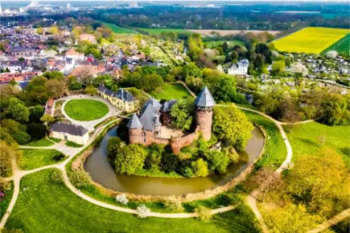 Vogelperspektive der Burg Linn in Krefeld bei Tag umgeben von Grünflächen.