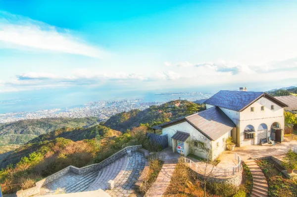 Die Aussicht über Kobe vom Mount Rokko aus bei Tag, mit einem weißen Haus, das auf dem Berg thront.