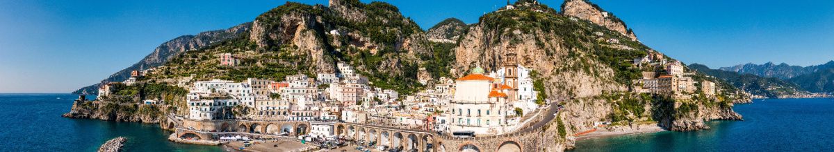 Eine Totale von Amalfi vom Ozean aus mit Bergen und Meer im Hintergrund bei Tag.