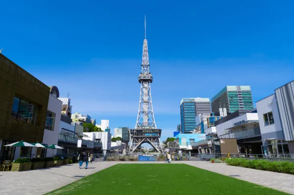 Ein Park in Nagoya Der Hisaya Odori Park in Nagoya mit einem Funkturm und Grünfläche am Tag.