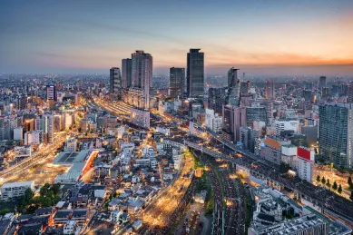 Blick über die Innenstadt von Nagoya mit zahlreichen Hochhäusern und beleuchteten Straßen bei Sonnenuntergang.