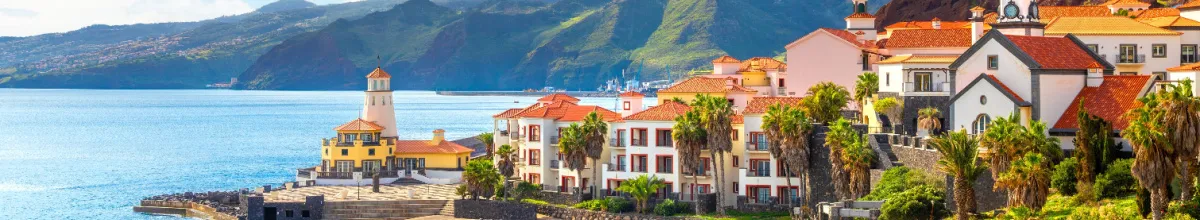 Ein Teil der Stadt auf einer Klippe, mit typischen rot-geziegelten Dächern und weißen Fassaden bei Tag mit dem Meer im Hintergrund.