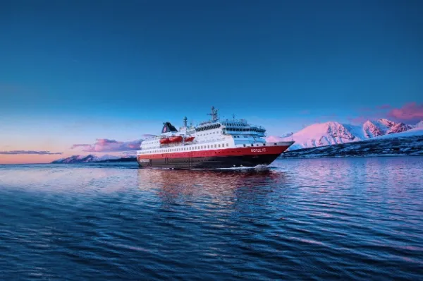 MS Nordlys Ein Schiff von Hurtigruten Expeditions fährt über das Meer in Norwegen bei Sonnenuntergang.