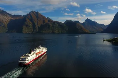 Ein Schiff der Hurtigruten-Flotte fährt durch einen Fjord in Norwegen.