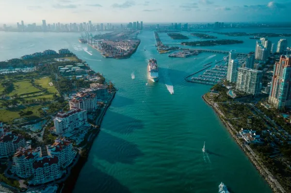 Ein Kreuzfahrtschiff kommt vom Kreuzfahrthafen von Miami zwischen den bebauten Inseln auf die Kamera zu.