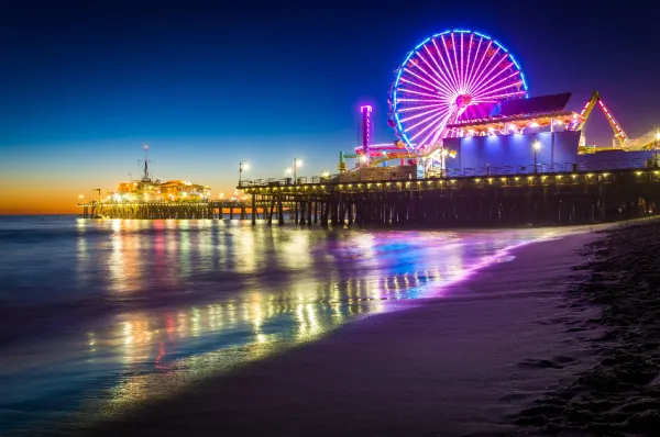 Santa Monica Der Santa Monica Beach bei Nacht mit einem beleuchteten Riesenrad und Vergnügungspark am Pier.