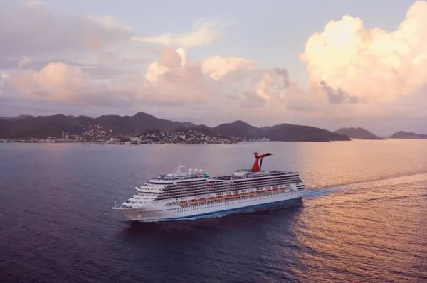 Die Carnival Valor vor Land bei Abendröte.