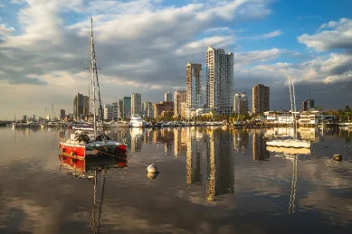 Der Hafen von Manila bei Sonnenaufgang mit einem Segelschiff und der Skyline im Hintergrund.