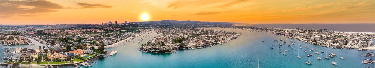 Eine Totale von Balboa Island mit der Hafenkante von Newport nebenan bei Sonnenuntergang.