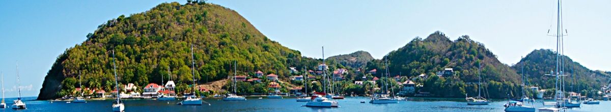 Inselpanorama mit grünen Hügeln und Segelbooten auf dem Meer.