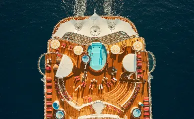 Aerial-Aufnahme des weitläufigen Sonnendecks von AIDAcosma mit Poollandschaft und gelben Sonnenschirmen – ein idealer Rückzugsort für Gäste der AIDA Angebote für Alleinreisende.