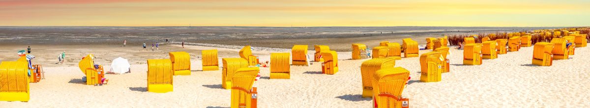 Strandkörbe am Wattenmeer bei Sonnenaufgang.