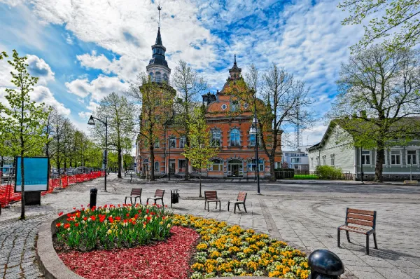 Ein Marktplatz in Rauma mit einem Blumenbeet und Sitzmöglichkeiten bei Tag.
