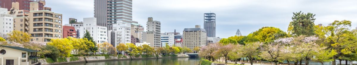 Die Innenstadt von Hiroshima mit vielen Bäumen und einem Kanal.