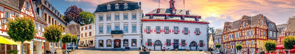 Ein Panorama des Marktplatzes von Linz am Rhein, mit bunten Häusern und einer untergehenden Sonne.