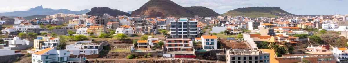 Kulisse von Praia mit vielen kleinen Häusern und einigen Hotels vor einer Hügellandschaft.