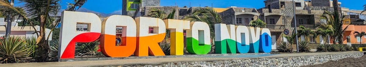 Das Wort Porto Novo in bunten Steinbuchstaben auf einer Mauer am Strand der Stadt.