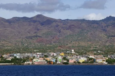 Blick auf die Stadt Porto Novo am Meer mit kleinen bunten Häusern vor einer bergigen Landschaft.
