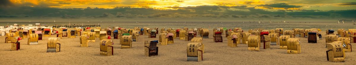 Der Strand bei Travemünde bei Sonnenuntergang, gespickt mit Strandkörben und der angrenzenden Ostsee im Hintergrund.