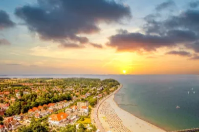 Vogelperspektive auf Travemünde mitsamt seinem Sandstrand und der angrenzenden Ostsee während der golden hour.