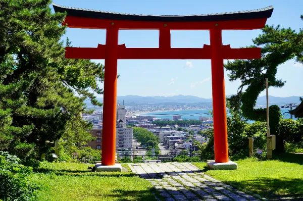 Ausblick über die Stadt Ausblick über Hakodate durch ein rotes Torii-Tor bei Tag.