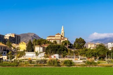 Blick auf eine Kirche auf einem Berg in Motril, die von der Sonne angestrahlt wird.