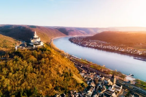 Taldorf mit Burg am Berg beim Rhein bei Sonnenuntergang.