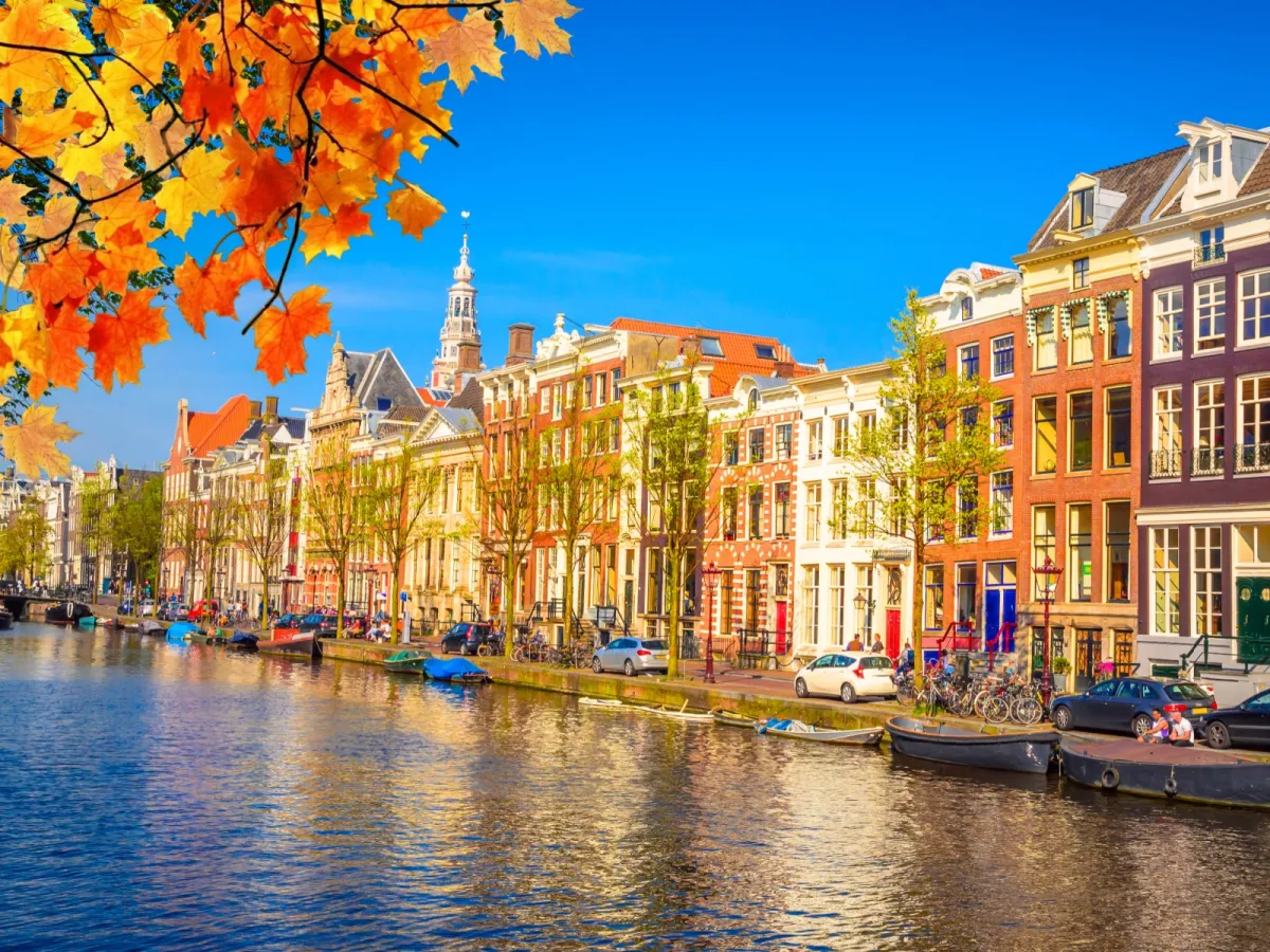 Amsterdams Innenstadt mit einer Gracht im Vordergrund an einem goldenen Herbsttag.