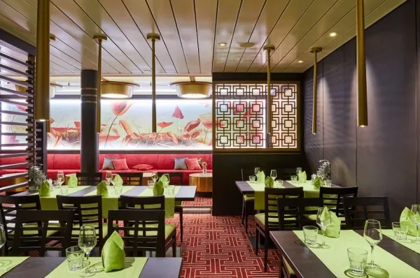 Bei einer Schiffsbesichtigung lernen Sie auch die Bordrestaurants kennen. Hier das East Restaurant auf AIDAnova. East Restaurant auf AIDAnova mit grün eingedeckten, dunklen Holztischen und -Stühlen, einem roten Teppichboden. Auch dieses Restaurant können Sie im Rahmen einer AIDA Schiffsbesichtigung entdecken.